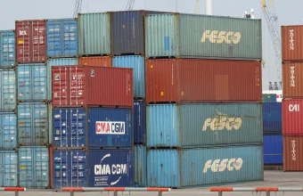 Stacked, brightly colored shipping containers from multiple carriers at a busy container terminal