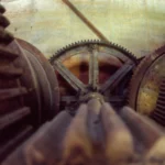 Close-up of large rusted cast-iron gears meshing together inside an old mining dredge