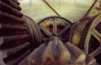 Close-up of large rusted cast-iron gears meshing together inside an old mining dredge