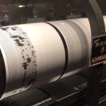 A drum seismograph recording a calm baseline pattern suddenly interrupted by a burst of erratic spikes