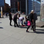 Con artists run a three-cup shell game on a table in Berlin, luring passersby to guess which cup hides the ball