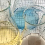 Chemistry lab conical flasks holding colored indicator solutions on a graph-paper background