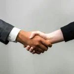 Two business people in suits shaking hands
