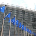 European Union flags flying outside the glass facade of the European Commission's Berlaymont building in Brussels