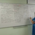 A person writes real analysis mathematical proofs on a whiteboard, illustrating formal mathematical proof work
