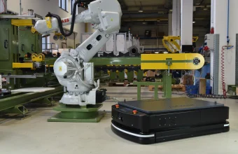 An ABB industrial robot arm and a black mobile AGV robot standing together on a factory floor