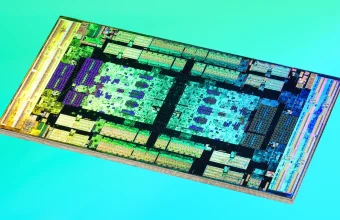 Microscope die shot of an AMD EPYC 7702 engineering sample I/O die, its circuit blocks glowing in teal, gold and violet