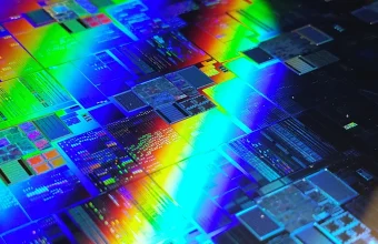 Macro photo of a silicon wafer showing individual chip dies illuminated by rainbow diffraction