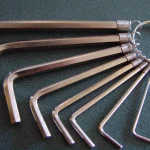 Eight silver hex keys of graduated sizes fanned out on a steel ring against a dark green surface
