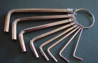 Eight silver hex keys of graduated sizes fanned out on a steel ring against a dark green surface