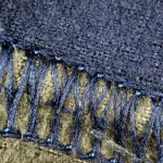 Macro photo of a machine-stitched seam joining two panels of blue fleece fabric