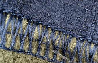Macro photo of a machine-stitched seam joining two panels of blue fleece fabric