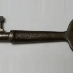 An antique iron skeleton key resting on a plain gray background