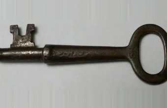 An antique iron skeleton key resting on a plain gray background