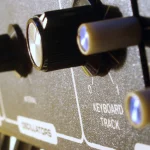 Close-up of labeled knobs and sliders on a Moog Rogue analog synthesizer control panel