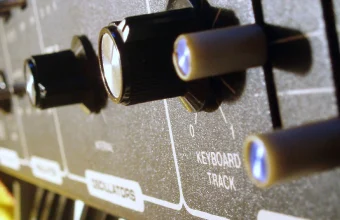 Close-up of labeled knobs and sliders on a Moog Rogue analog synthesizer control panel