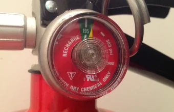 A fire extinguisher pressure gauge showing the needle in the charged green zone, a check that confirms a safety device actually works rather than just assuming it does