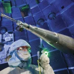 A researcher in a cleanroom suit works inside the spherical laser fusion target chamber at Lawrence Livermore's National Ignition Facility