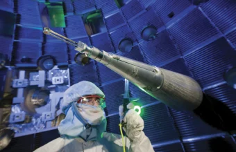 A researcher in a cleanroom suit works inside the spherical laser fusion target chamber at Lawrence Livermore's National Ignition Facility