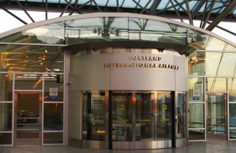 A revolving door at the entrance of Portland International Airport, used as a visual metaphor for the constant churn of enterprise AI vendor re-evaluation