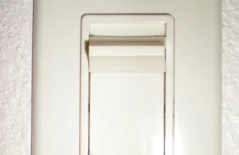 A physical slide dimmer light switch positioned partway along its track, next to a wall outlet plate