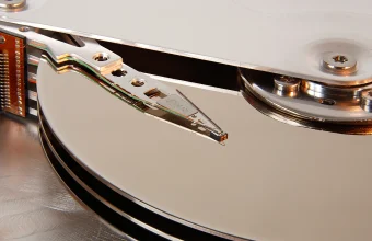 Macro photo of an open hard disk drive showing the read-write head suspended just above a reflective platter