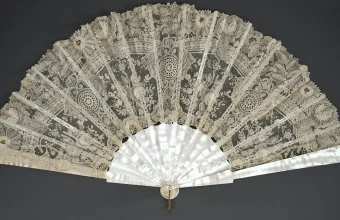 An antique mother-of-pearl and lace folding fan fully spread open against a dark background, a visual metaphor for fanning one query into many
