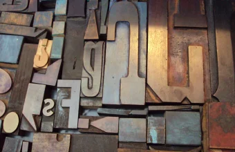 Close-up of jumbled wooden letterpress printing type blocks in different letterforms and shapes