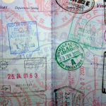 A densely stamped passport page showing dozens of overlapping international entry and exit stamps, visas, and immigration marks