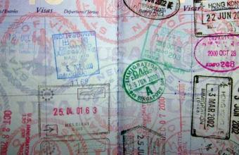 A densely stamped passport page showing dozens of overlapping international entry and exit stamps, visas, and immigration marks