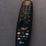 An LG Android TV remote lying on a fabric surface, showing dedicated Netflix and Prime Video buttons alongside colored quick-access buttons
