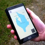 A hand holds a smartphone displaying a map navigation app outdoors, illustrating mobile location data.