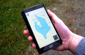 A hand holds a smartphone displaying a map navigation app outdoors, illustrating mobile location data.