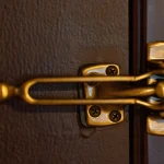 Brass swing-bar door lock, a secondary latch, mounted on a hotel room door
