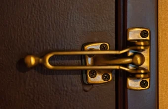 Brass swing-bar door lock, a secondary latch, mounted on a hotel room door