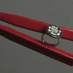 A silver signet ring engraved with a coat of arms between two sticks of red sealing wax on a grey surface
