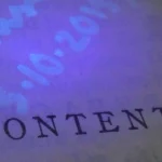 A page of printed text beside handwritten notes that are invisible in normal light but glow under an ultraviolet lamp