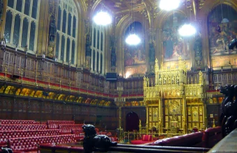 The gilded chamber of the House of Lords at the Palace of Westminster, with red benches and the ceremonial canopy visible