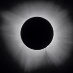 Total solar eclipse showing a dark lunar disc surrounded by a bright white corona against a black night sky