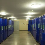 Rows of numbered blue storage lockers in a station corridor, a literal metaphor for shared storage reused across many different occupants