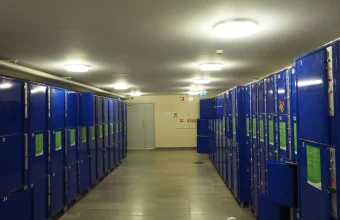 Rows of numbered blue storage lockers in a station corridor, a literal metaphor for shared storage reused across many different occupants