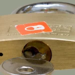 A brass padlock with its key inserted into the lock cylinder