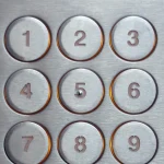 Close-up of a metal numeric keypad on a building entry access-control panel