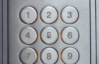 Close-up of a metal numeric keypad on a building entry access-control panel
