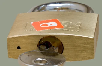 A brass padlock with its key inserted into the lock cylinder