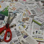 A pile of grocery coupons with a pair of red-handled scissors, representing the discount Meta offers developers who share their AI usage data