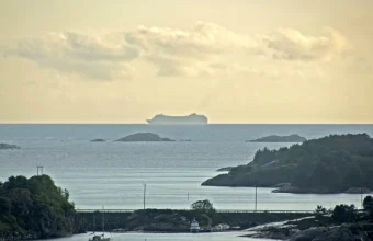 A cargo ship's silhouette distorted into an elongated shape by an atmospheric superior mirage above the horizon at sea