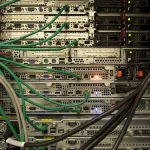 Dense green and black network cabling plugged into rack-mounted servers in a data center