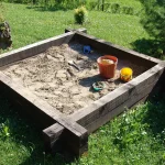 OpenAI Pauses Training of Its Most Capable Models for the Second Time in Three Months A real wooden outdoor sandbox filled with sand and toys, empty of people