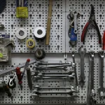 A wall-mounted pegboard with wrenches, pliers, and hand tools neatly organized in rows